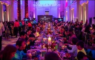 Long communal dinner table with theatrical purple lighting